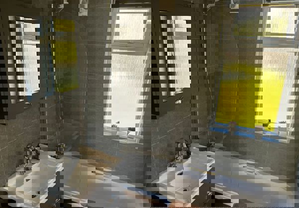 Sleek modern bathroom with tub and integrated shower, and dark grey tiles throughout