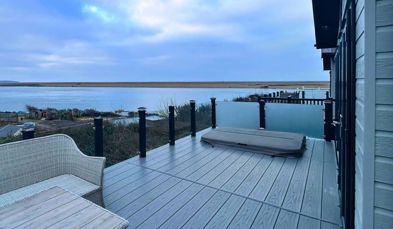 External of a caravan decking with hot tub, outdoor furniture and seaviews