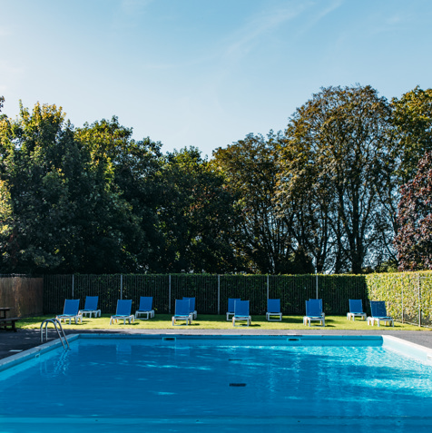 An outdoor pool with a sun terrace and sun loungers on a sunny day