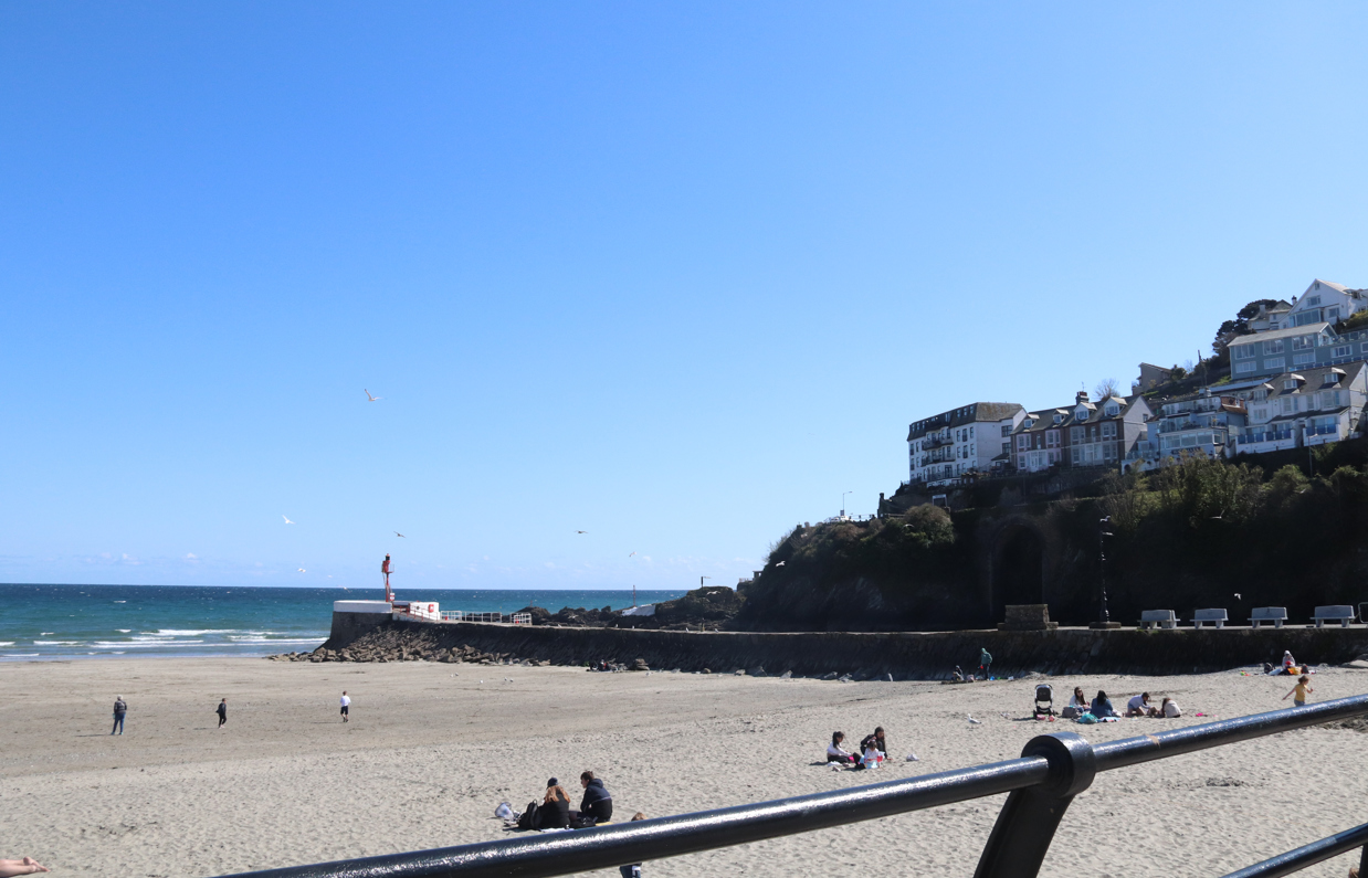 The view out towards the sea and Banjo Pier from Looe Beach on a sunny, blue sky day