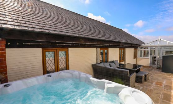 External of a cottage outside area with hot tub, conservatory and outdoor furniture