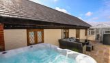 External of a cottage outside area with hot tub, conservatory and outdoor furniture