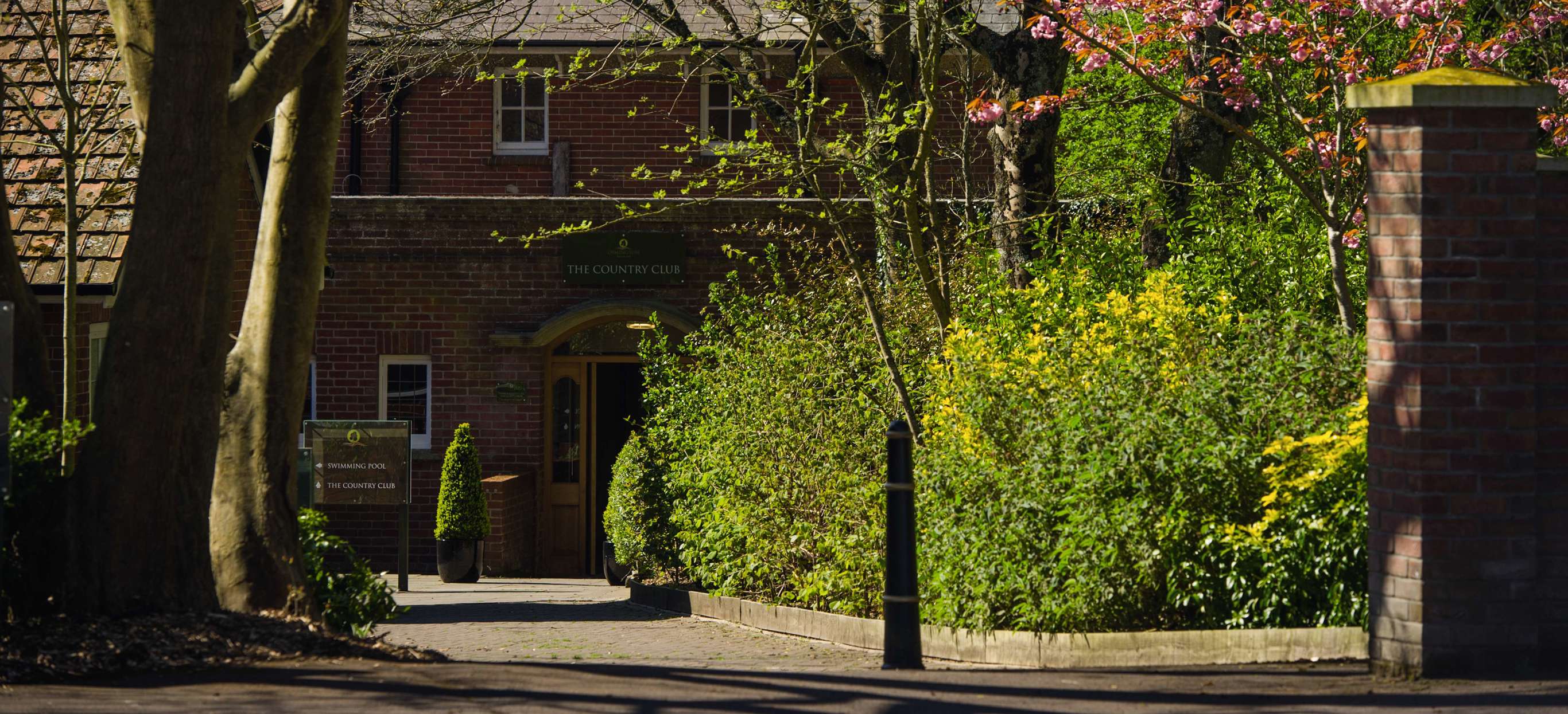 The entrance to The Country Club among countryside, trees and flowers