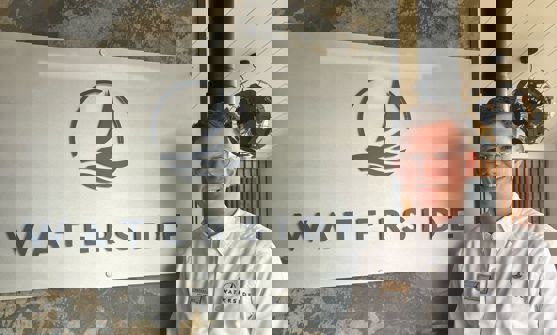 A smiling man stood beside a Waterside sign