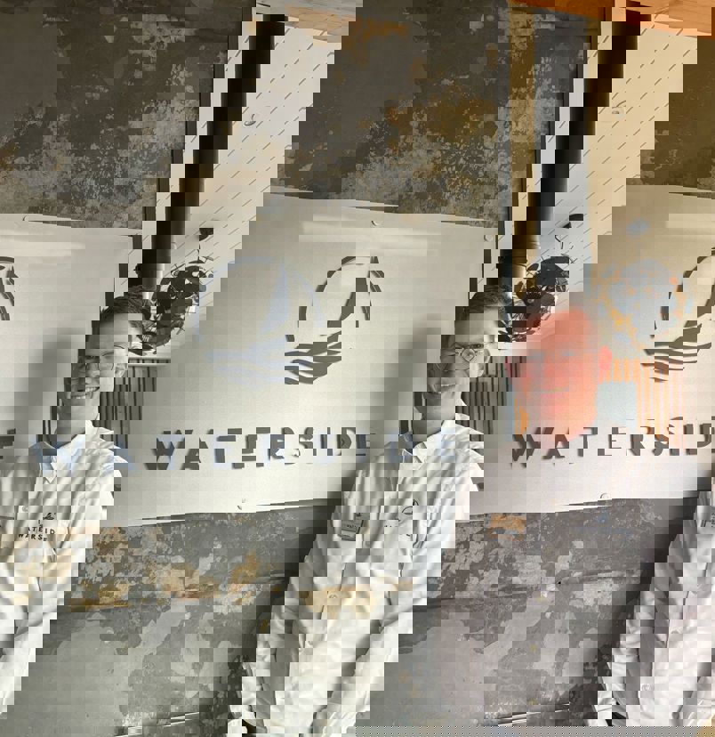 A smiling man stood beside a Waterside sign