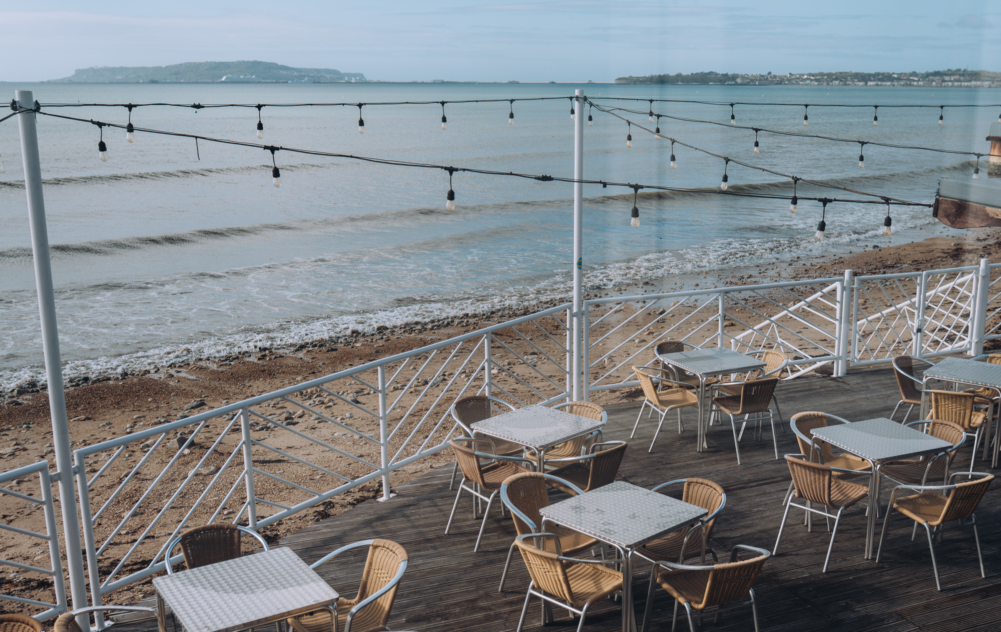 The outdoor seating beach bar area of Drift Bar & Grill with fairy lights and views of the sea, Weymouth Bay and Portland