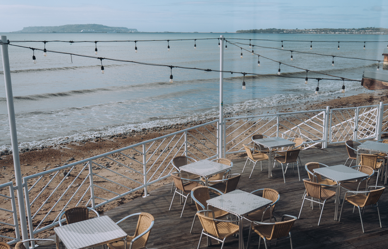 The outdoor seating beach bar area of Drift Bar & Grill with fairy lights and views of the sea, Weymouth Bay and Portland