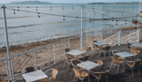 The outdoor seating beach bar area of Drift Bar & Grill with fairy lights and views of the sea, Weymouth Bay and Portland