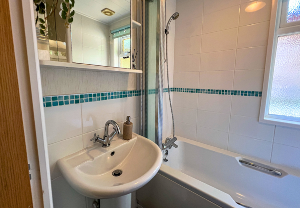 Internal of a lodge bathroom with shower over bath and sink