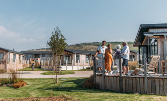 A family on holiday enjoying time together on the decking of a lodge among rolling countryside