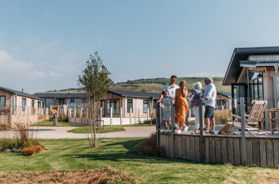 A family on holiday enjoying time together on the decking of a lodge among rolling countryside