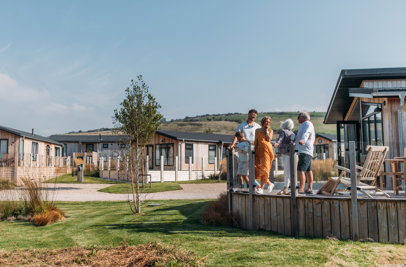 A family on holiday enjoying time together on the decking of a lodge among rolling countryside