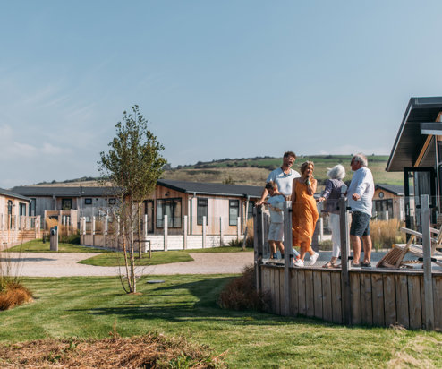 A family on holiday enjoying time together on the decking of a lodge among rolling countryside