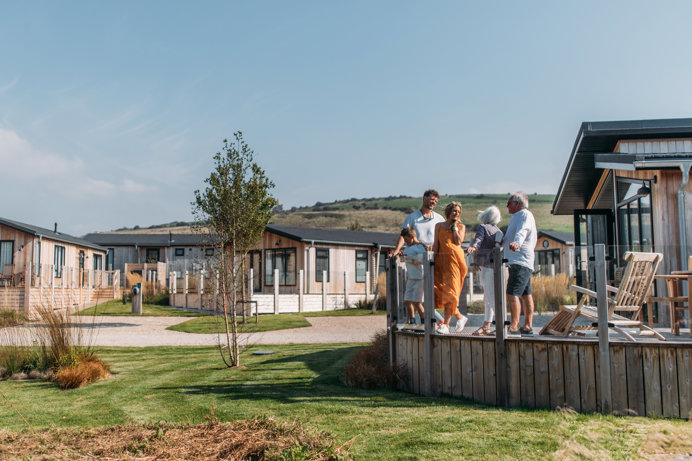A family on holiday enjoying time together on the decking of a lodge among rolling countryside