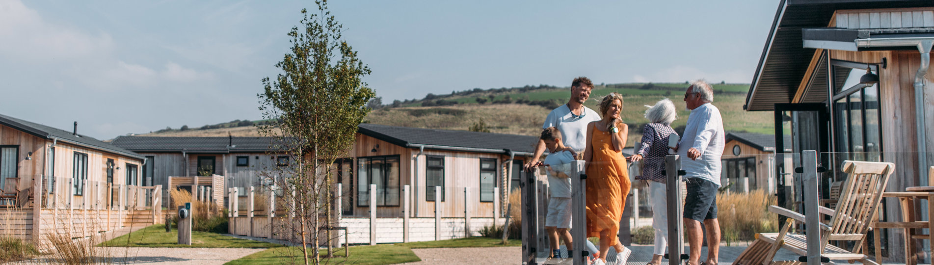 A family on holiday enjoying time together on the decking of a lodge among rolling countryside