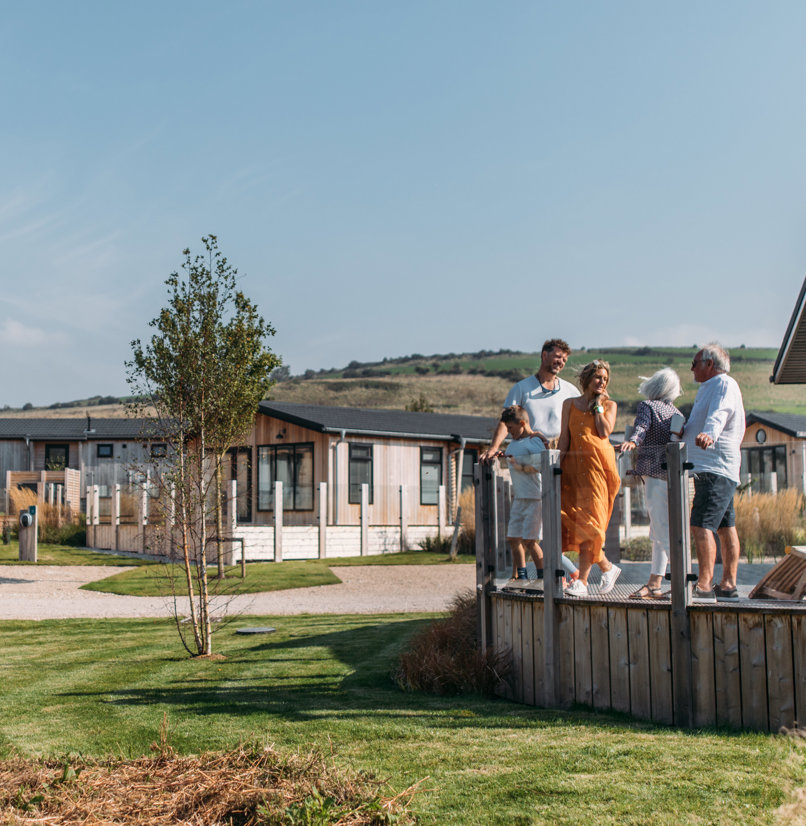 A family on holiday enjoying time together on the decking of a lodge among rolling countryside
