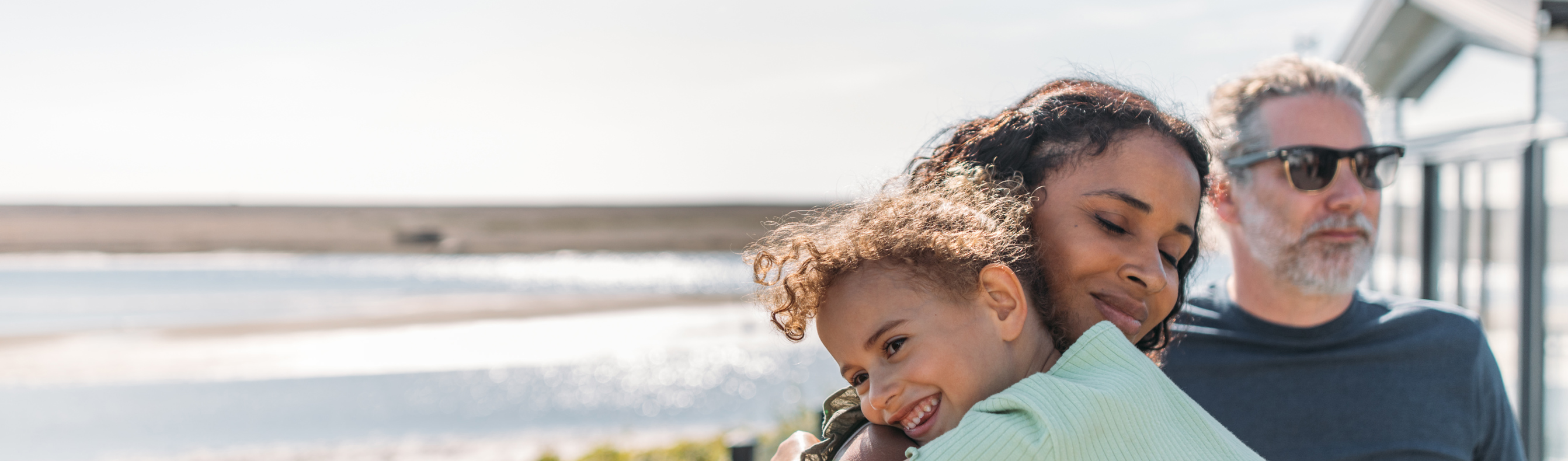 Mother and daughter cuddle while family enjoy view from deck at Chesil Beach