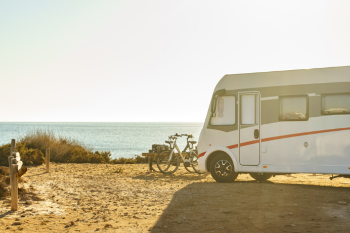 A motorhome by the coast with bicycles beside it on a sunny day