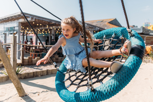 A young girl playing on a swing at an outdoor play park
