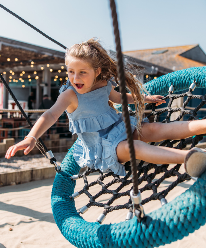 A young girl playing on a swing at an outdoor play park