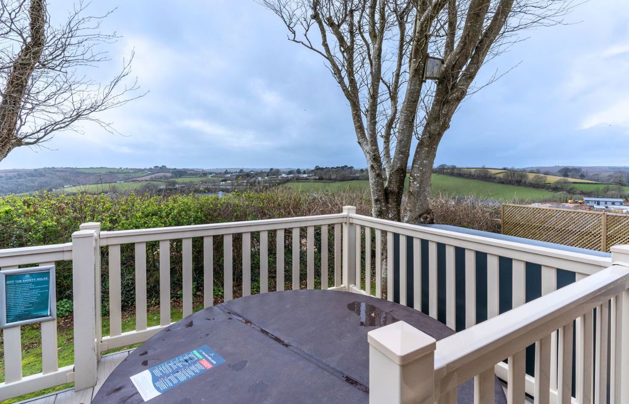 External of a lodge on pitch with decking and a hot tub with countryside views