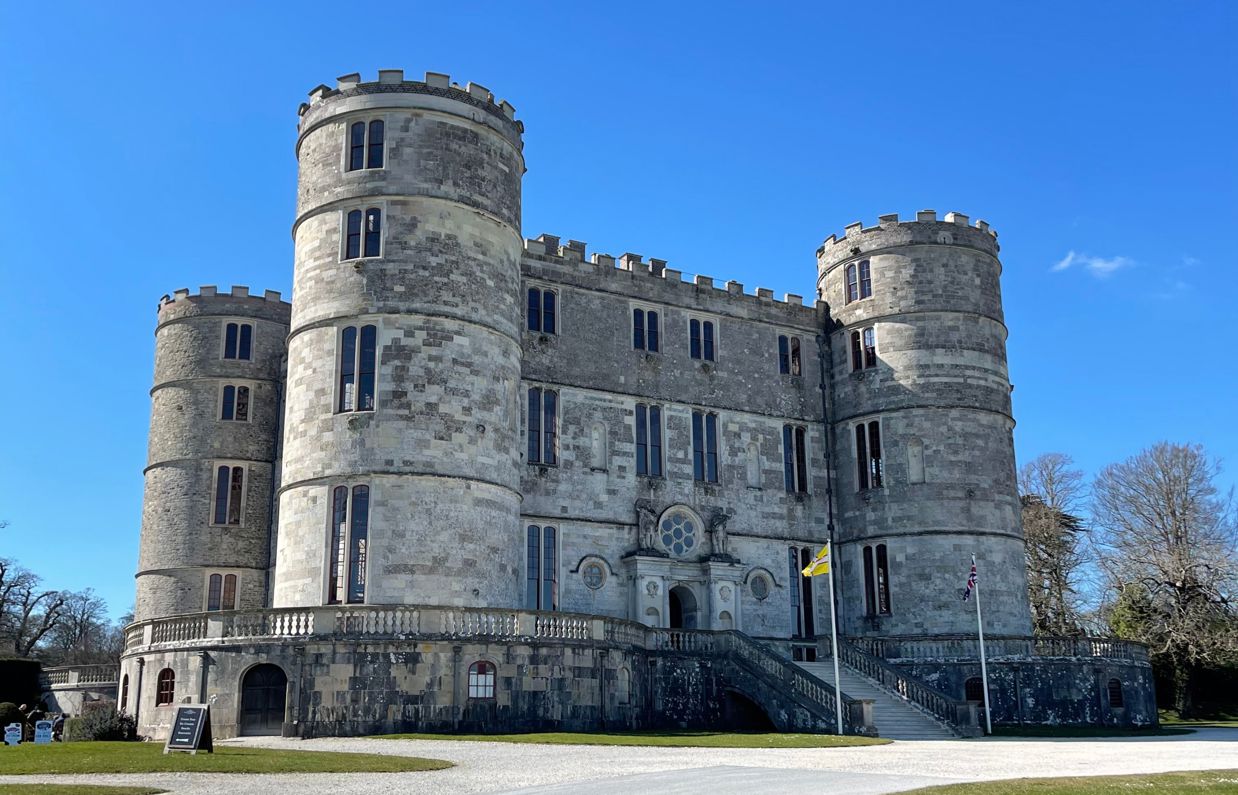 A stunning large castle on a blue sky day with multiple floors and turrets