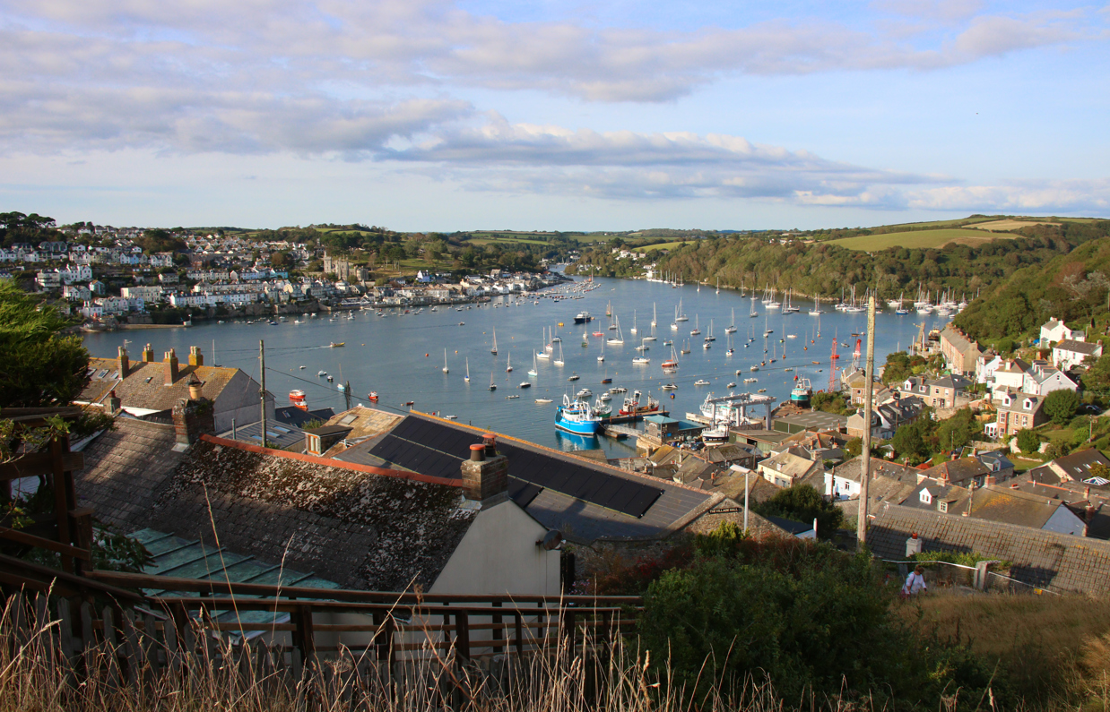 The view of Fowey from Polruan with many boats in the water and rolling hills in the distance