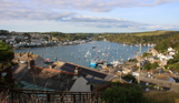 The view of Fowey from Polruan with many boats in the water and rolling hills in the distance