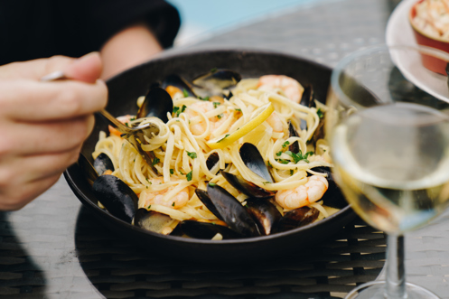 A seafood linguini dish with a glass of white wine