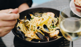 A seafood linguini dish with a glass of white wine