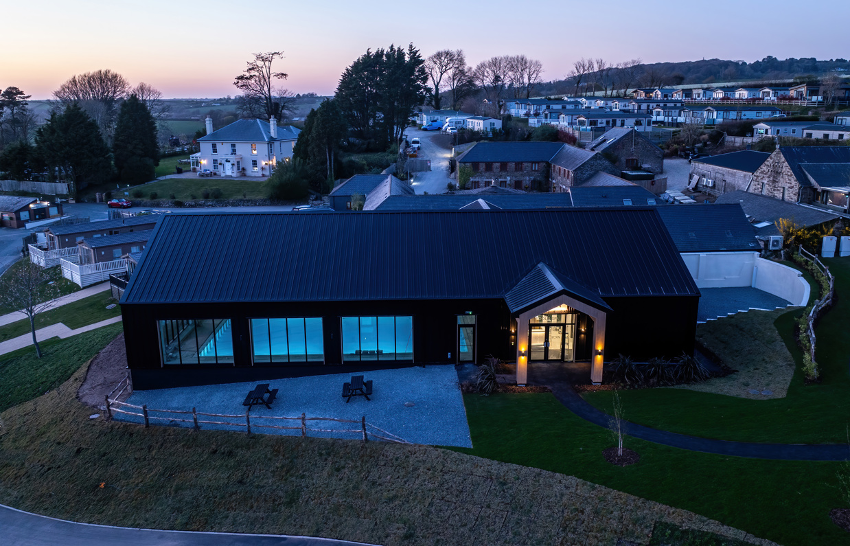 Aerial view of an indoor heated swimming pool within a barn style building with boho-chic styling and countryside views