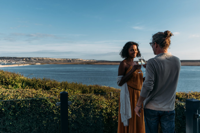 Couple toasting with Chesil Beach in background