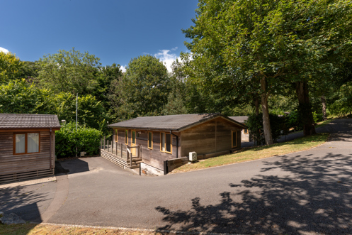 A secluded road on a lodge park with trees and lodges on a sunny, blue sky day