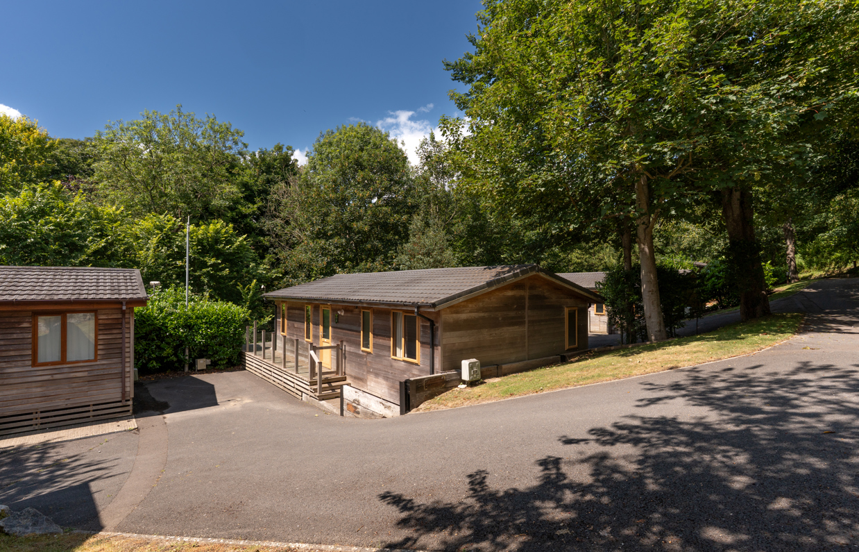 A secluded road on a lodge park with trees and lodges on a sunny, blue sky day