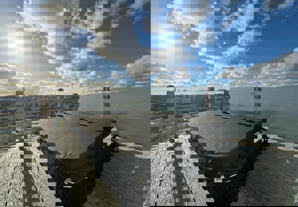 Large hot tub on decking overlooking valley