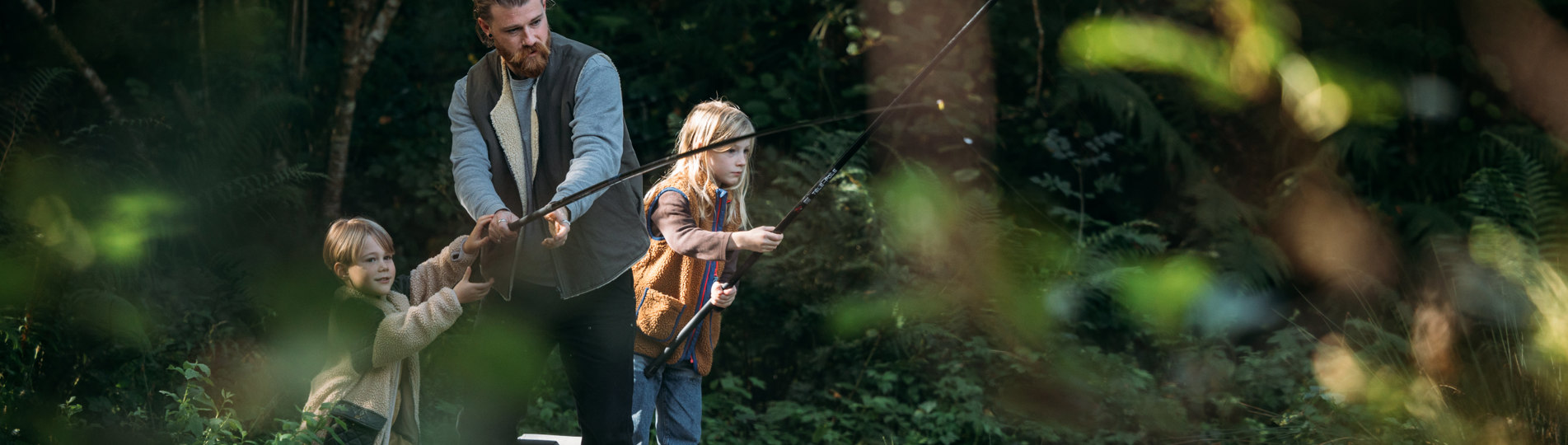 A father and two young boys at a lake among woodland fishing