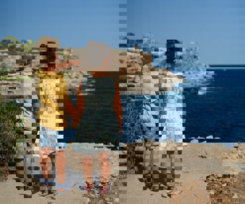 A young boy and girl standing on the edge of the coast path holding hands whilst the young boy points out to sea
