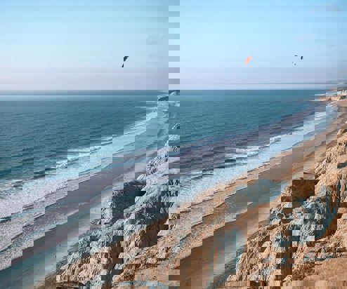 A long stretch of beach with rocky cliffs and blue waters