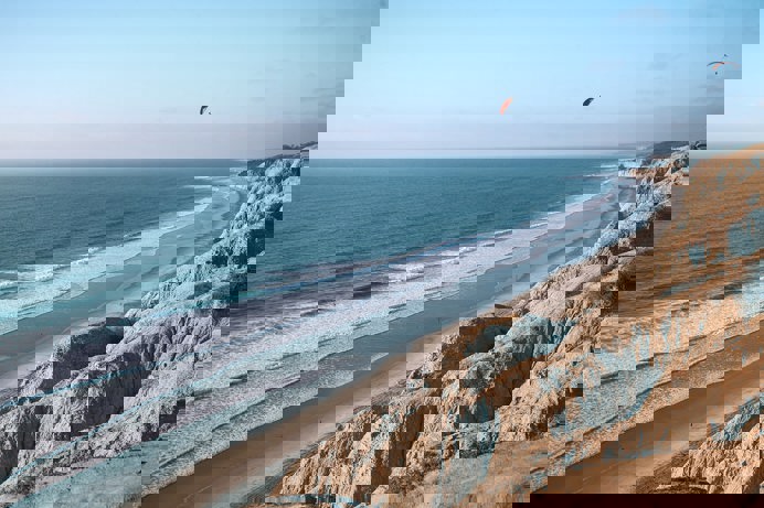 A long stretch of beach with rocky cliffs and blue waters