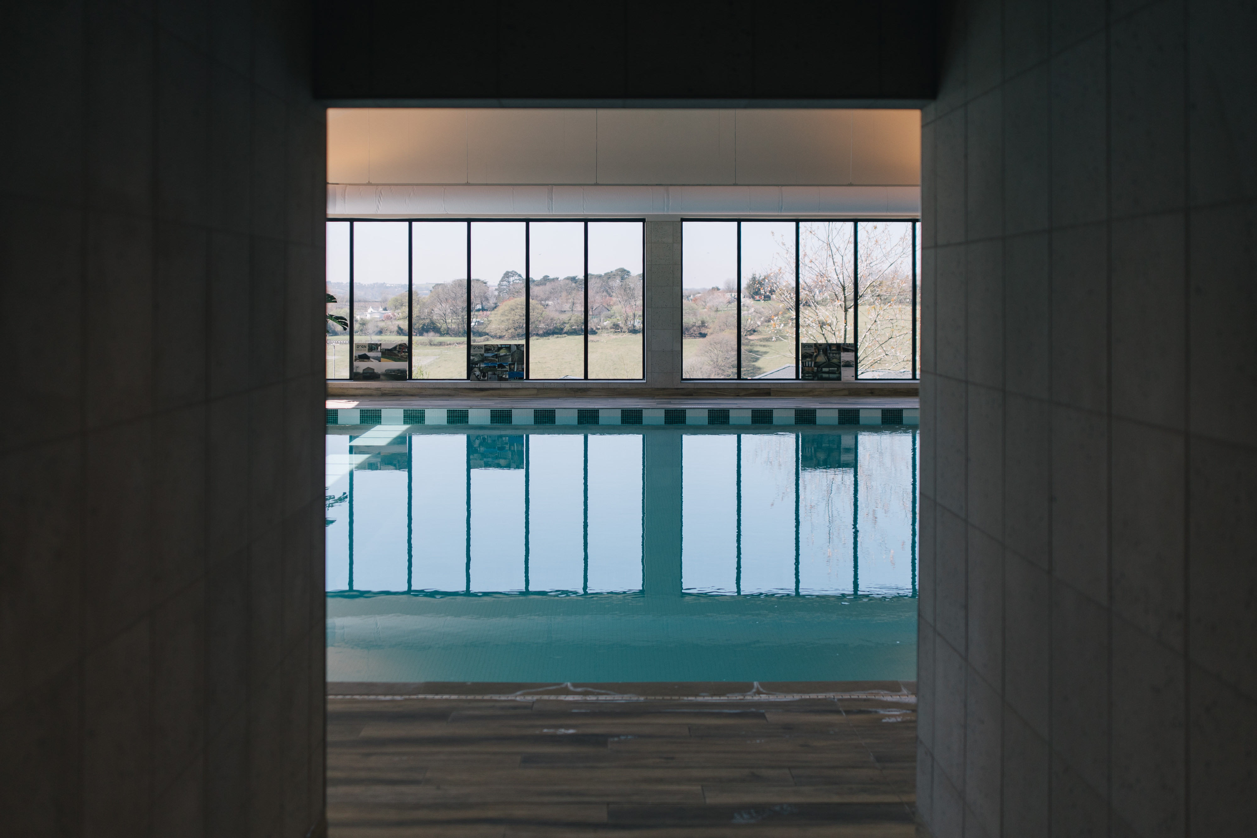 An indoor heated swimming pool within a barn style building with boho-chic styling and countryside views