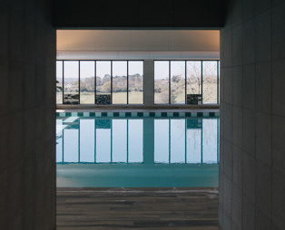 An indoor heated swimming pool within a barn style building with boho-chic styling and countryside views