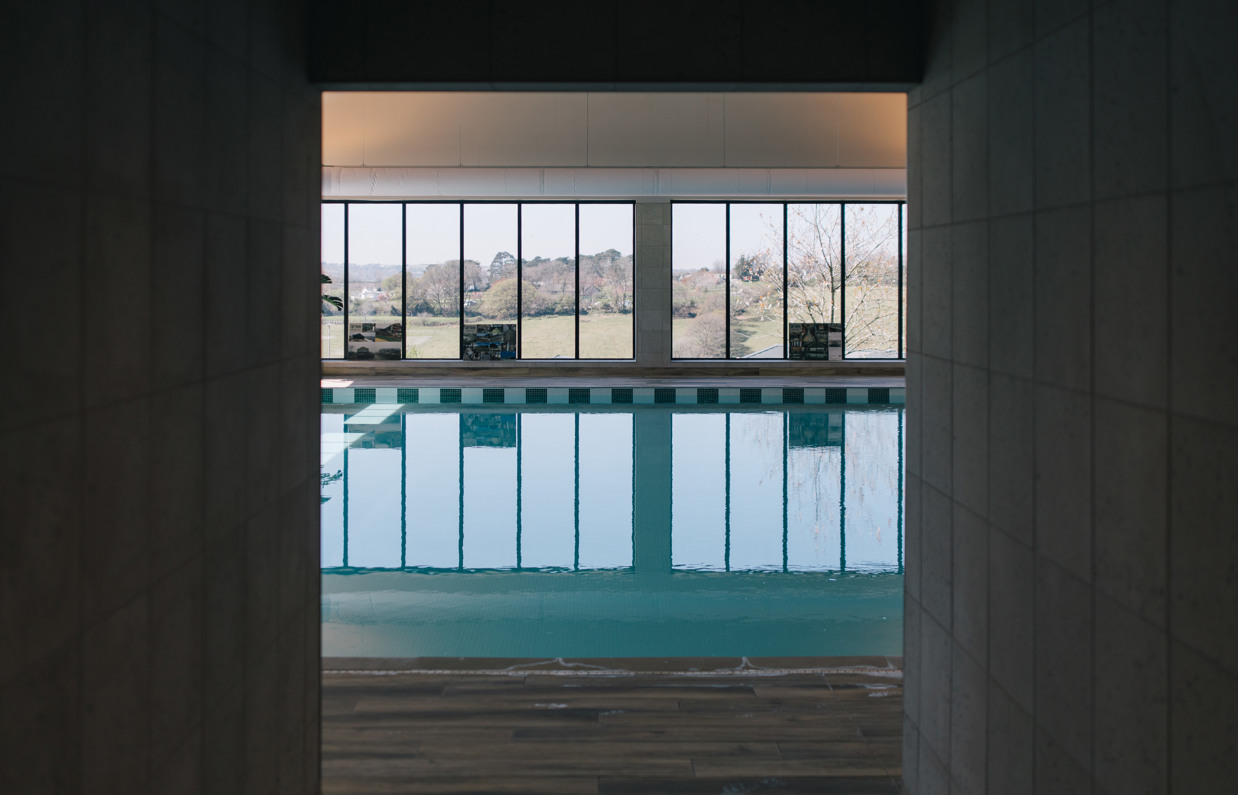 An indoor heated swimming pool within a barn style building with boho-chic styling and countryside views