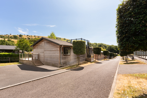An open road on a lodge park with trees, rolling countryside hills and lodges on a sunny, blue sky day