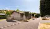 An open road on a lodge park with trees, rolling countryside hills and lodges on a sunny, blue sky day