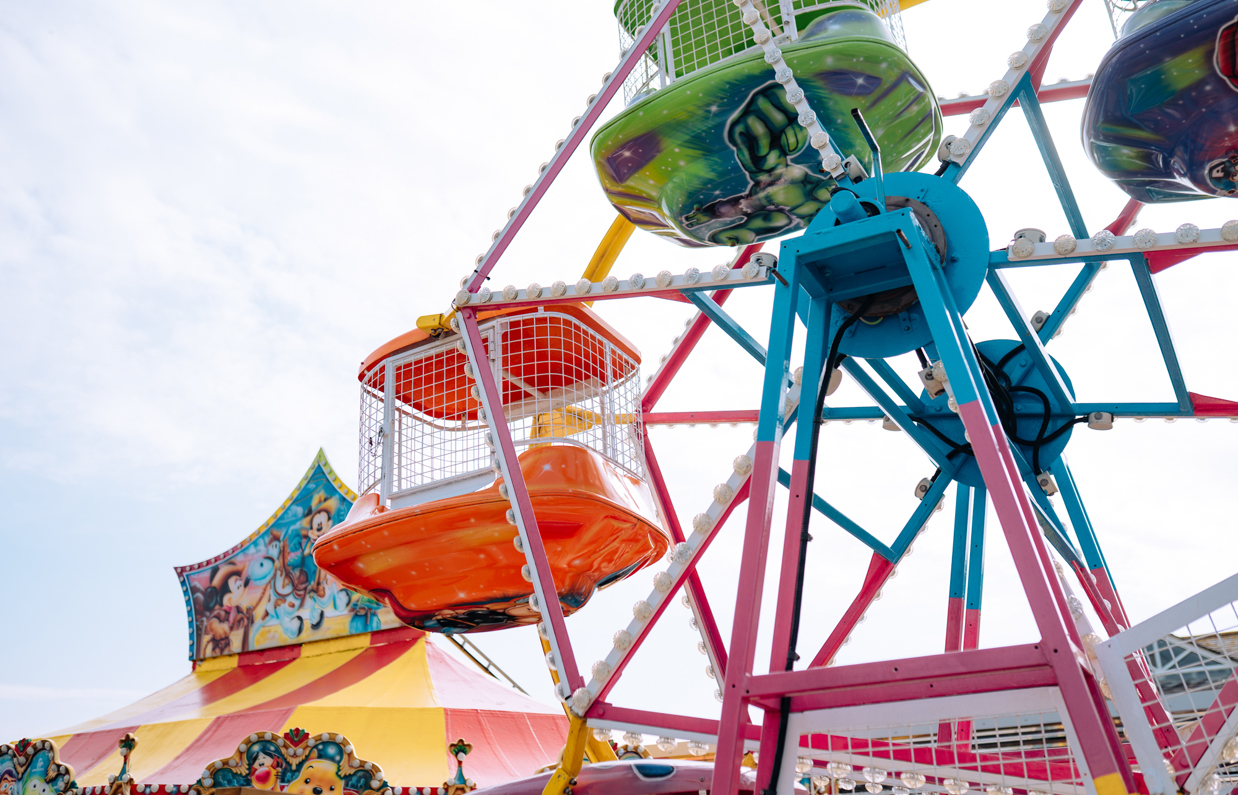 A ferris wheel for small children at Southside Funfair with other rides in the background