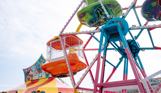 A ferris wheel for small children at Southside Funfair with other rides in the background