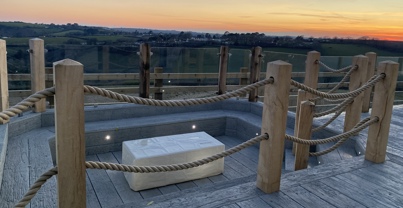 Sunken fire pit on decking looking over valley at sunset
