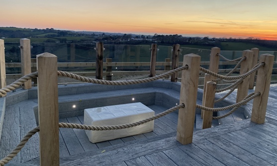 Sunken fire pit on decking looking over valley at sunset