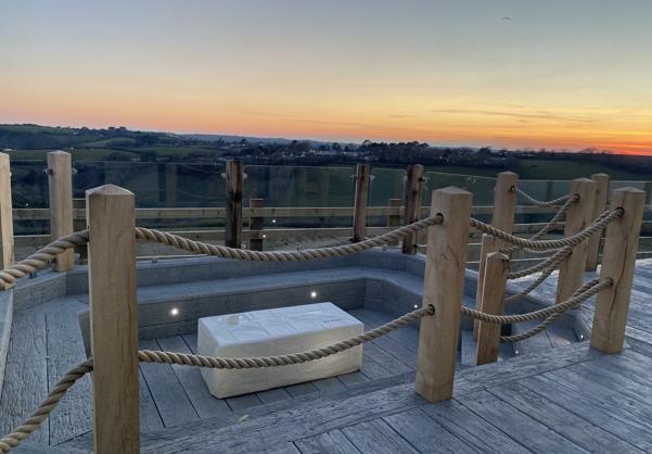 Sunken fire pit on decking looking over valley at sunset