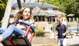 A young girl being pushed on a swing by her dad at the country club